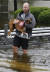 27일(현지시간) 미국 텍사스(Texas)주 갤버스턴카운티(Galveston County)에 있는 리그시티에서 한 남성이 반려견을 안고 물에 잠긴 자신의 집에서 탈출하고 있다.[AP=연합뉴스]
