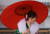 붉은 양산을 든 일본의 한 여성이 8일 도쿄의 한 공원에서 열린 성인식에 참석해 활짝 웃고 있다.[ AP=연합뉴스]