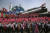 북한 남녀가 지난해 4월 15일 평양 김일성광정에서 열렸던 열병식에서 북극성 미사일 형태의 모형을 뒤로하고 플라스틱 꽃을 흔들며 행진하고 있다. [AP=연합뉴스]