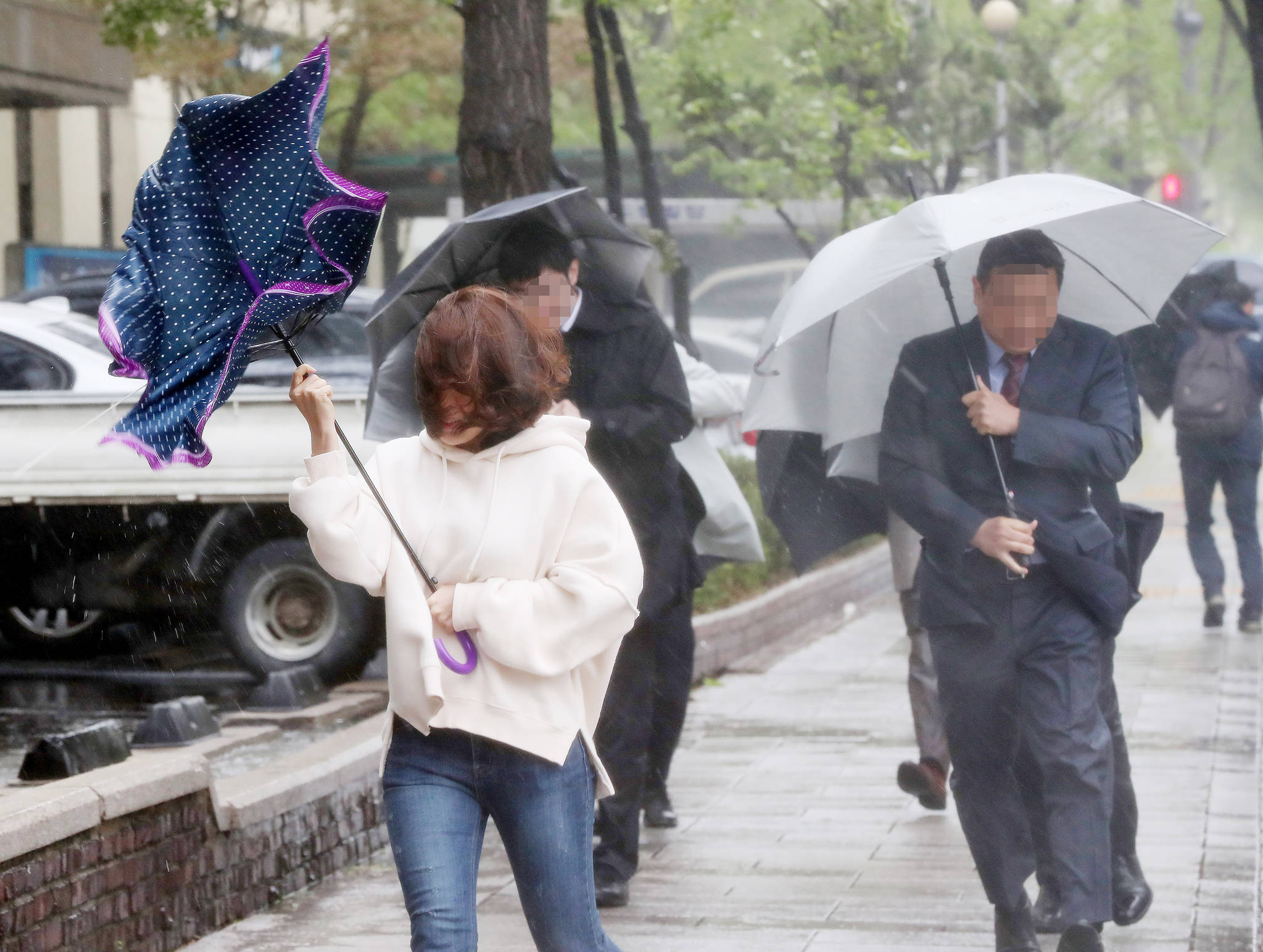 전국 대부분 지역에 비가 내린 23일 오전 서울 외교부 인근에서 시민들이 갑자기 불어온 강풍으로 우산을 제대로 펴지 못한채 걸음을 옮기고 있다. 우상조 기자