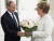 독일의 앙겔라 메르켈 총리(오른쪽)이 지난 18일 러시아 남부 소치에서 블라디미르 푸틴 러시아 대통령을 만나 꽃다발을 받고 있다. [로이터=연합뉴스]