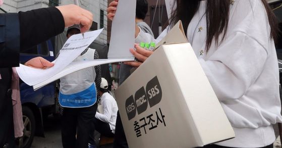 제20대 국회의원선거일인 13일 서울 중구 명동 주민센터에 마련된 명동 제1투표소 앞에서 방송3사의 출구조사원들이 유권자들을 상대로 출구조사를 하고 있다. 