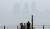 해무가 발생한 20일 부산 남구 이기대를 찾은 관광객들이 멀리 희미하게 보이는 해운대 마린시티를 배경으로 기념촬영을 하고 있다. 송봉근 기자