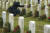 15일 미국 알링턴 국립묘지 60구역 에서 자원봉사자들이 묘비에 화환을 놓고 있는 동안 한 방문자가 비석 앞에서 애도하고 있다.[EPA=연합뉴스]