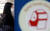 5일 서울 성북구 안암역 승강장에 설치된 구호용품 보관함의 방독면 그림 뒤로 마스크를 착용한 시민이 보인다. [뉴시스]