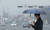 서울 및 수도권 지역에 초미세먼지 주의보가 발령된 12일 오전 서울 여의도에서 마스크와 우산을 쓴 시민이 발걸음을 옮기고 있다. [뉴스1]