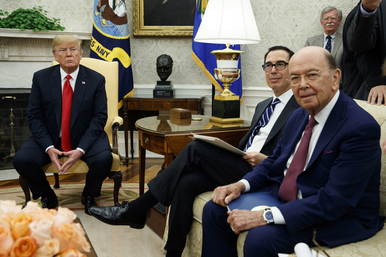 도널드 트럼프 미 대통령(오른쪽)이 스티븐 므누신 재무장관, 윌버 로스 상무장관(왼쪽)과 함께 지난해 7월 백악관에 앉아있는 모습. [AP]