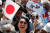 나루히토 일왕의 즉위를 축하하기 위해 고쿄에 들어선 한 여성이 양손에 각각 일장기(히노마루)와 새 연호인 &#39;레이와(令和)&#39;가 적힌 부채를 들고 기뻐하고 있다. [로이터=연합뉴스]