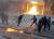 11일(현지시간) 알바니아 수도 티라나의 정부 청사 건물에 반정부 시위대들이 터트린 휘발유 폭탄으로 불길이 치솟고 있다. 정부 청사 건물이 불길과 최루탄 연기로 자욱한 가운데 방독면을 쓴 경찰들이 폭발을 피해 다급히 움직이고 있다. [EPA=연합뉴스]