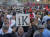 11일(현지시간) 알바니아 수도 티라나의 한 광장에서 시민들이 반정부 메시지가 담긴 손팻말을 들고 집회를 하고 있다. [AP=연합뉴스]