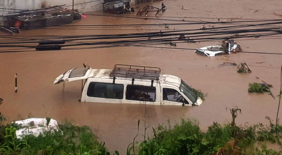 12일(현지시간) 네팔 카트만두 시내를 관통하는 강이 폭우로 범함하자 강변에 주차돼 있던 차량들이 떠내려가고 있다. [신화=연합뉴스]