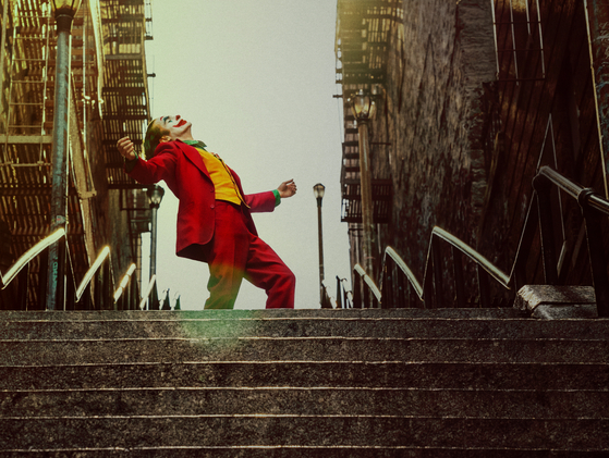 아서가 광대 분장을 한 채 계단을 뛰어내려오는 모습. 다음 장면에서 그는 우상인 토크쇼 진행자 머레이(로버트 드 니로)에게 자신을 &#39;조커&#39;라 불러달라 말한다. [사진 워너브러더스 코리아]