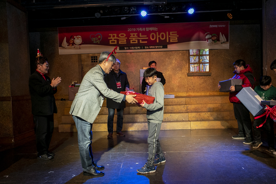 ‘몰래몰래 산타 되기’에 참여한 한국암웨이 임직원들이 아이들에게 선물을 전달하는 모습. [사진 한국암웨이 미래재단]