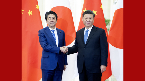 시진핑 중국 국가주석과 아베 신조 일본 총리가 지난해 12월 베이징 중일 정상회담에 앞서 악수를 나누고 있다. 중국은 최근 일본과의 관계 개선에 적극성을 보이고 있다. [중국 신화망 캡처]