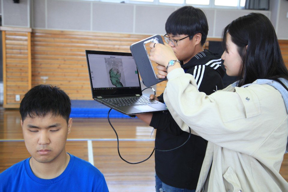 탈북 청소년 대안학교인 드림학교 고등학생들이 3D 프린팅 기술을 이용해 얼굴 모형을 완성하기 위해 전북맹아학교 졸업반 학생의 얼굴을 스캔하고 있다. [사진 전북맹아학교]