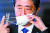 아베 일본 총리가 6일 관저에서 기자회견을 하기 위해 마스크를 벗고 있다. [로이터=연합뉴스]