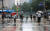 비가 내리는 지난달 22일 오전 서울 종로구 광화문 세종대로 사거리에서 우산을 쓴 출근길 시민들이 횡단보도 신호를 기다리고 있다. 연합뉴스