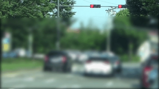 지난달 5일 A씨의 차량(오른쪽 흰색 차량)이 적색 신호등이 켜졌을 때 횡단보도를 지나는 장면이 경찰 단속 캠코더에 잡혔다. 실제로는 적색등이 켜져있지만 경찰이 찍은 영상에는 신호등이 깜빡이는 상태로 보인다. [인천지방경찰청]