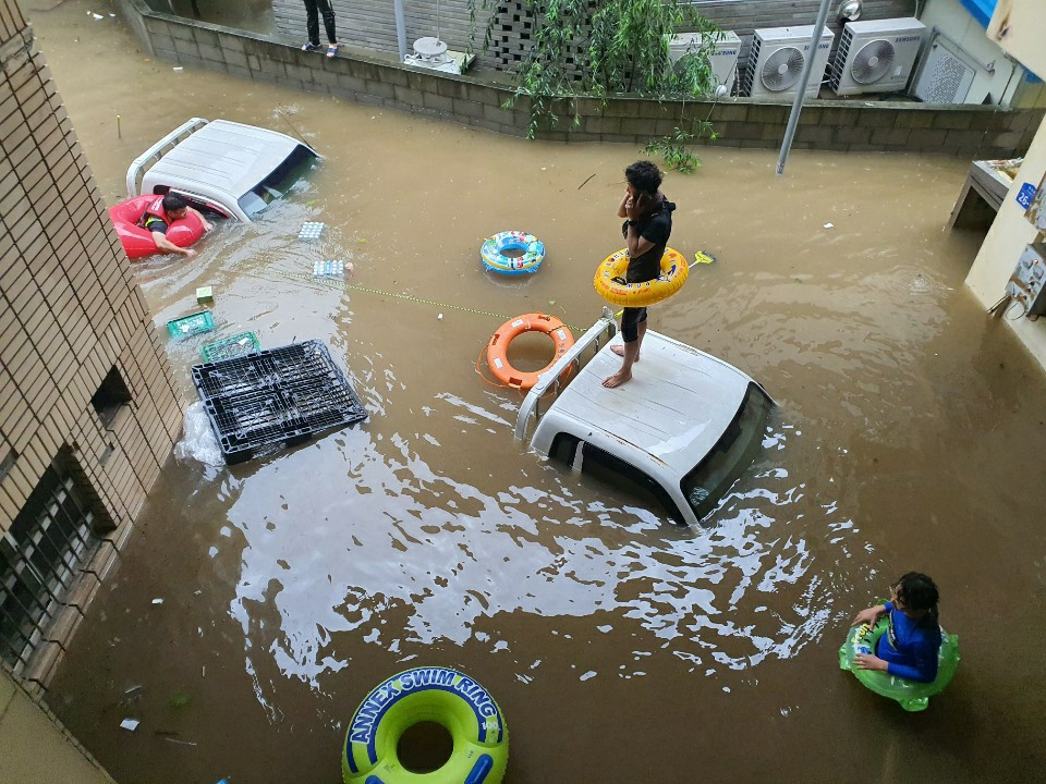 폭우가 내린 8일 오후 경남 하동군 화개장터에서 튜브를 착용한 시민이 구조를 기다리고 있다. [연합뉴스]