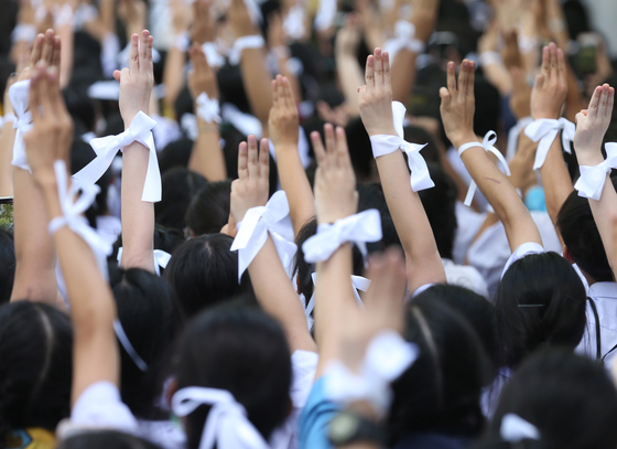 지난 19일 태국 방콕에서 열린 반정부 시위에서 태국 10대 학생들이 흰색 리본을 묶고 세 손가락 경례를 하고 있다. 세 손가락 경례와 흰 리본은 '반정부 시위에 동참'한다는 의미다. 이들은 군사정권에 맞서 정치 개혁을 촉구하고 있다. [EPA=연합뉴스]