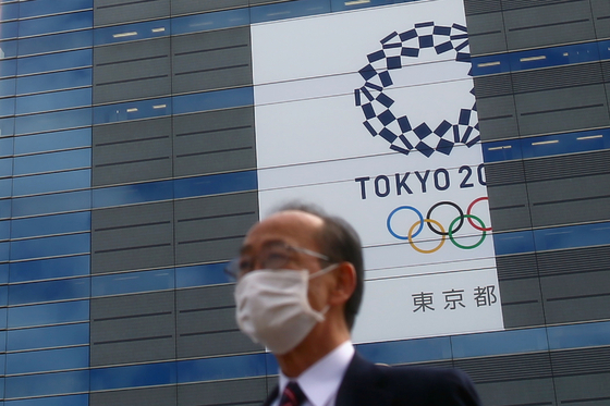 마스크를 쓴 채 도쿄올림픽 배너 앞을 지나는 도쿄 시민. [로이터=연합뉴스] 