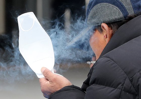  9일 서울역 광장에서 한 시민이 한 손에 마스크를 들고 담배를 피고 있다. [뉴스1]