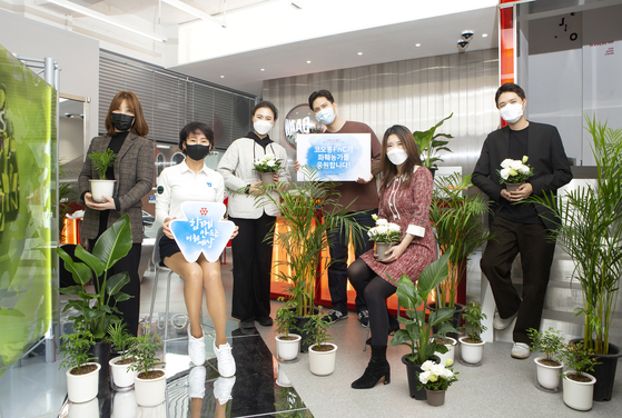 코오롱FnC 이규호 전무가 플라워 버킷 챌린지 캠페인에 참여해 전국 대리점에 화분을 선물했다. 왁(WAAC) 도산점 매장에서 직원들이 화분을 들고 포즈를 취하고 있다. 사진 코오롱FnC  