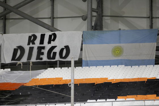 A banner and the Argentinian flag in memory of Diego Maradona are pictured before the Champions League group C soccer match between Olympique Marseille and FC Porto at the Velodrome stadium in Marseille, southern France, Wednesday, Nov.25, 2020. Diego Maradona, the Argentine soccer great who scored the "Hand of God" goal in 1986 and led his country to that year's World Cup title before later struggling with cocaine use and obesity, has died. He was 60. (AP Photo/Daniel Cole)  〈저작권자(c) 연합뉴스, 무단 전재-재배포 금지〉