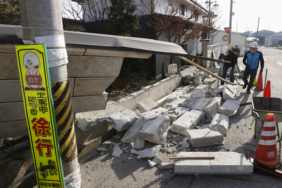 14일 일본 후쿠시마시 쿠니미에서 주민들이 지진으로 무너진 돌담을 정리하고 있다. [AP=연합뉴스]