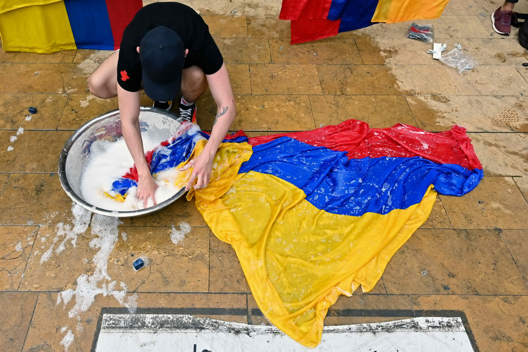 콜롬비아 메데인시의 시위대가 3일 두케 대통령의 세제 개혁안에 대한 저항의 표시로 국기를 세탁하고 있다. AFP=연합뉴스