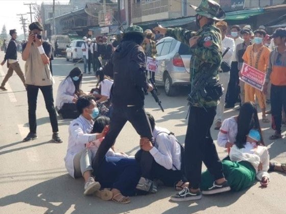 지난 2월 28일(현지시간), 첫 대규모 사상자가 나온 미얀마 '피의 일요일'의 한 장면. 부상자를 현장에서 돕던 의료진이 시민을 향해 총을 겨누는 군경의 다리를 붙잡고 총을 쏘지 말라고 애원하고 있다. [SNS 갈무리] 