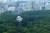 16일 일본 도쿄 요요기공원 나무숲 사이로 떠오르고 있는 공공미술 열기구 ‘마사유메’(正夢). AFP=연합뉴스