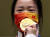 도쿄올림픽 대회 1호 금메달 양첸이 금메달을 마스크 앞에 갖다 대고 있다. [로이터=연합뉴스]