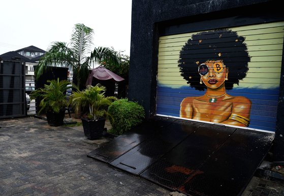 지난 7월 나이지리아 수도 라고스의 한 야외 전시장에 아프리카 여성이 암호화폐가 그려진 선글라스를 쓴 여성의 그림이 그려져 있다. [AFP=연합뉴스]