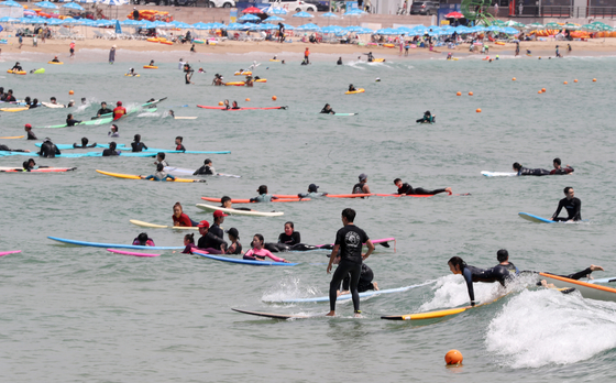 지난달 30일 오후 부산 송정해수욕장을 찾은 서퍼들이 서핑을 즐기고 있다. [연합뉴스]