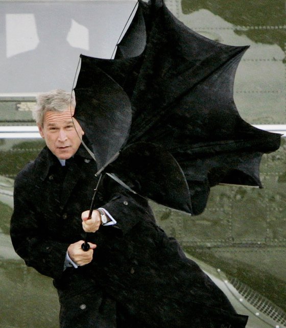 지난 2004년 조지 부시 전 미국 대통령이 앤드루스 공군기지에서 전용기에 탑승하기 전 비바람에 날아가는 우산을 잡으려 안간힘을 쓰고 있다. 로이터=뉴시스