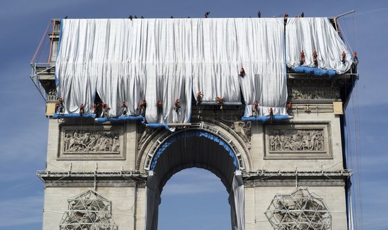 Workers wrap the Arc de Triomphe monument, Sunday, Sept. 12, 2021 in Paris. The ″L'Arc de Triomphe, Wrapped″ project by late artist Christo and Jeanne-Claude will be on view from, Sept.18 to Oct. 3, 2021. The famed Paris monument will be wrapped in 25,000 square meters of fabric in silvery blue, and with 3,000 meters of red rope. (AP Photo/Rafal Yaghobzadeh)