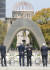 2016년 4월 일본 히로시마에서 열린 G7 외무장관 회담에 참석한 케리 미국 국무장관(왼쪽에서 둘째)과 기시다 후미오 외상이 히로시마 평화공원 기념비 앞에서 서로 허리와 등에 손을 들려 다독거리고 있다. 뒤로 보이는 것이 원폭 돔이다. [지지통신 제공] 