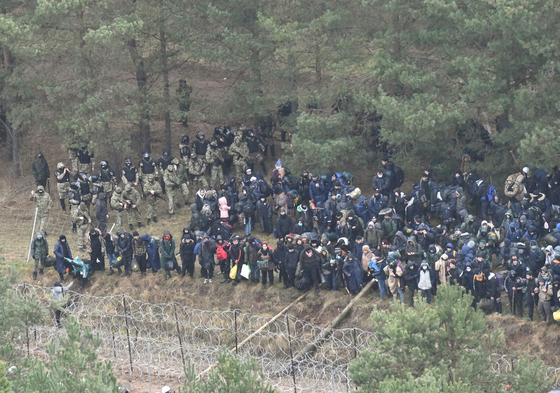 8일(현지시간) 벨라루스 국경에 모인 난민들이 철조망 너머 폴란드 쪽을 바라보고 있다. [로이터=연합뉴스]