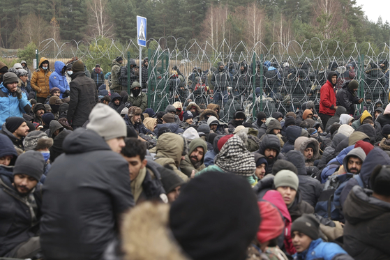 지난 15일 벨라루스-폴란드 국경 쿠즈니차 검문소 앞에서 난민들이 철조망 앞에 모여 있다. 연합뉴스