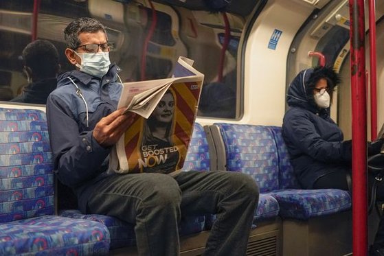 영국 런던 지하철에서 한 시민이 마스크를 착용한 채 신문을 읽고 있다. [AP=연합뉴스]