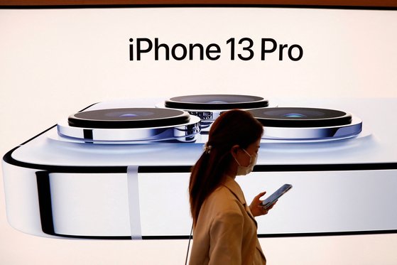 지난 9월 중국 베이징에서 한 여성이 애플의 신제품 아이폰13 프로가 전시된 광고판 앞을 지나가고 있다.[로이터=연합뉴스]
