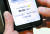 4일 서울 은평구 청구성심병원에서 한 시민이 휴대전화로 코로나19 백신 예방접종 정보를 확인하기 위해 QR 화면을 보고 있다. [뉴스1]