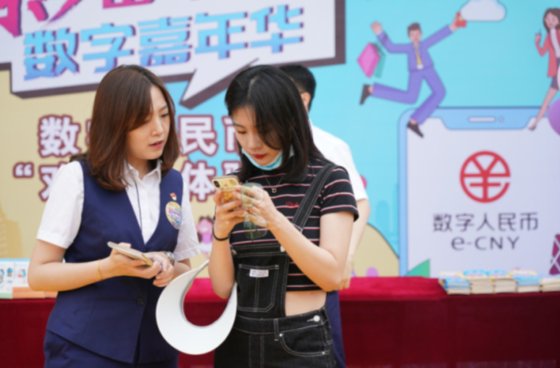 중국 교통은행 베이징 지점 소속 은행원(사진 왼쪽)이 6월 16일 한 여행객에게 디지털 위안화 지갑 개설 방법을 알려주고 있다 