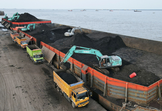 지난달 13일 인도네시아 자카르타 북부에 위치한 항구에서 인부들이 바지선에 선적한 석탄을 트럭에 옮겨싣고 있다. 인도네시아는 자국 내 수요가 급증하자 지난달 초부터 석탄 수출을 금지했다. 이에 따라 전 세계 석탄 가격이 급등했다. [로이터]