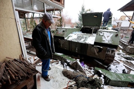 지난 1일(현지시간) 우크라이나 키이우 인근 부차 마을 주민이 군용 차량 옆에 숨져 있는 러시아군 병사의 시신을 바라보고 있다. AP=뉴시스