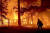 미국 캘리포니아주 플루머스 카운티에서 지난해 12월 24일(현지시간) '딕시'란 이름의 대형 산불이 주택을 불태우고 있는 화재 현장을 한 소방관이 지나고 있다. 미 서부 13개 주에서는 극심한 가뭄에 폭염이 겹치면서 80여 건의 산불이 발생해 주변으로 번지고 있다. [AP=연합뉴스]