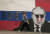 세르비아에서 푸틴이 그려진 벽화 앞을 지나가는 시민. AP=연합뉴스 