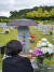 2015년 8월 서울 구파발 검문소 총기사고로 순직한 고 박세원 수경의 어머니가 국립대전현충원 아들 묘비에 우산을 씌우고 추모하고 있다. 순직의무군경 유가족은 별도의 기념일 제정을 요구하고 있다. 사진 박세원 수경 유족 등