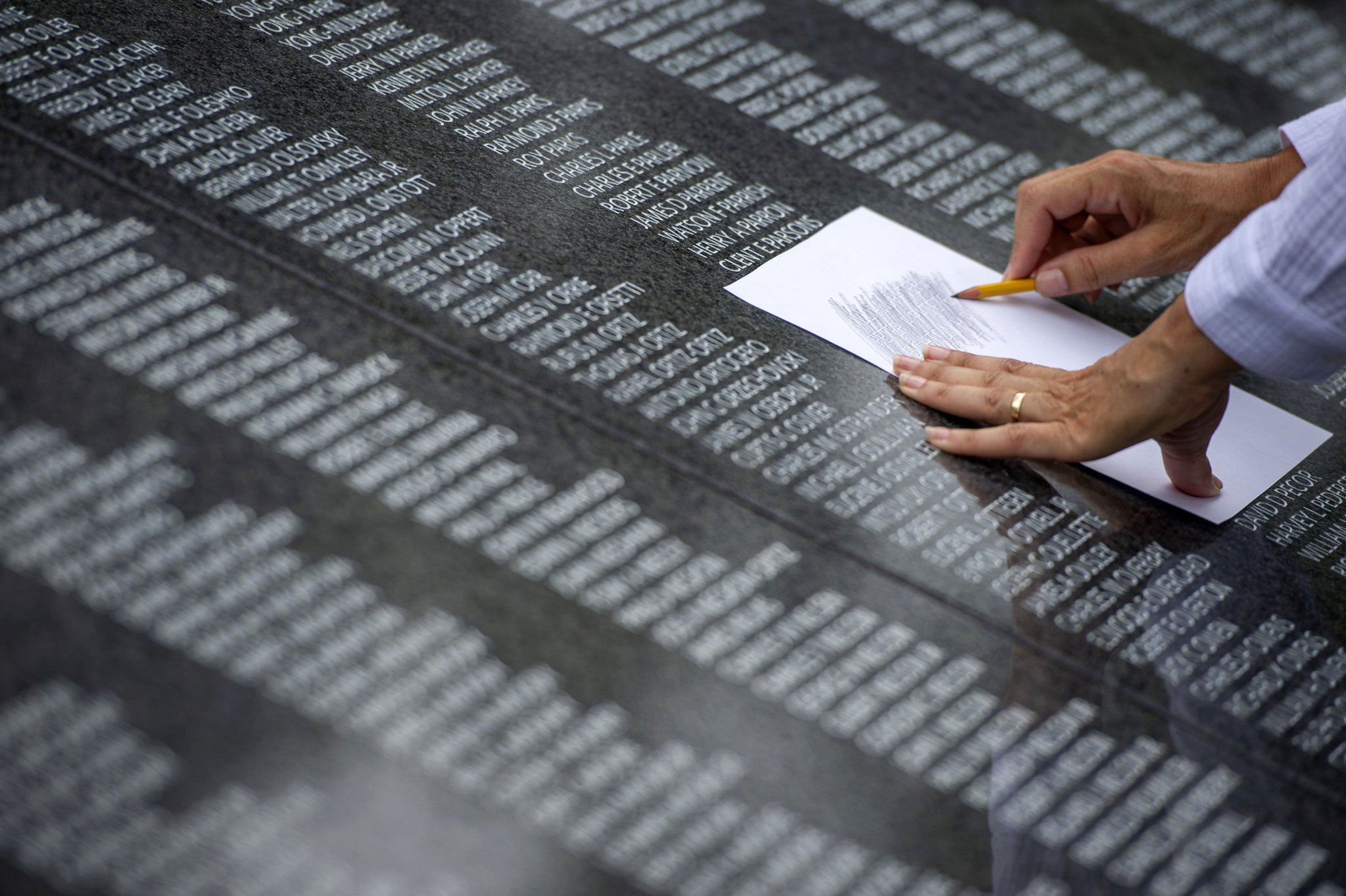 한국전 참전용사 유가족이 27일(현지시간) ‘추모의 벽’에서 화강암에 새겨진 이름을 종이에 옮기고 있다.UPI=연합뉴스